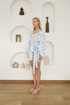 Full-length view of Mermaid Muse kaftan in cerulean blue and white mermaid tile print with self-tie belt and side slits
